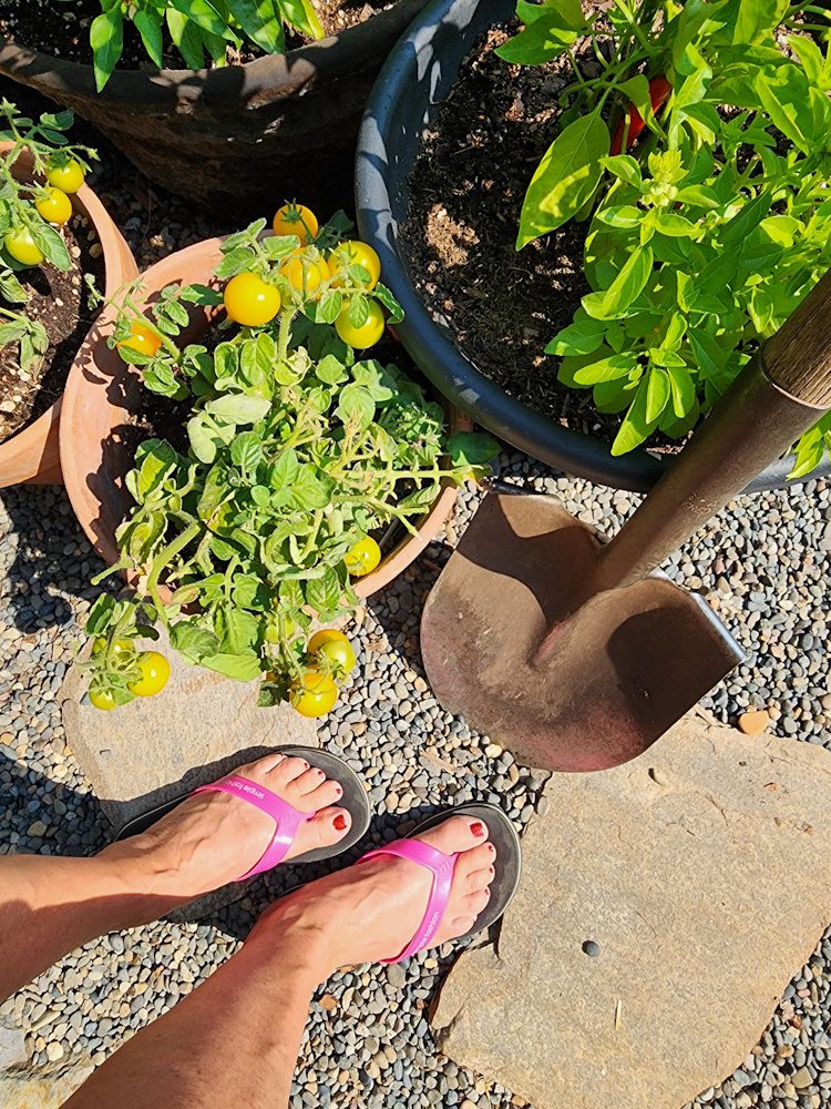 feet in flipflops in the garden with a shovel